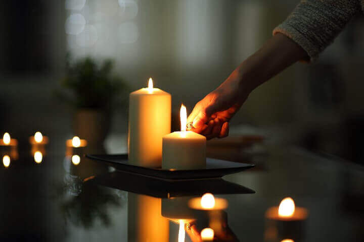 Woman Lighting Candle In Dark